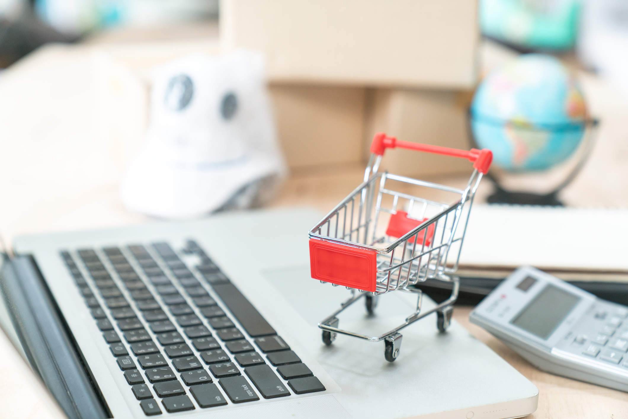 Online shopping concept. Shopping car, laptop on the desk